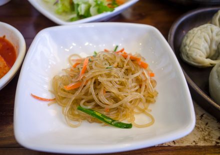 명절 전날 부엌에서 당면과 여러 채소를 준비해 잡채를 만드는 장면