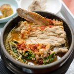점심 식당 테이블에 큰 감자탕 냄비와 개인용 뼈해장국 뚝배기가 함께 놓인 모습