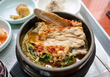 점심 식당 테이블에 큰 감자탕 냄비와 개인용 뼈해장국 뚝배기가 함께 놓인 모습