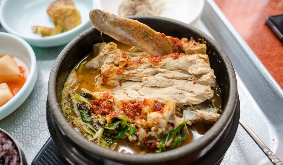 점심 식당 테이블에 큰 감자탕 냄비와 개인용 뼈해장국 뚝배기가 함께 놓인 모습