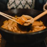 일식집 메뉴판 옆에 놓인 따뜻한 우동 한 그릇
