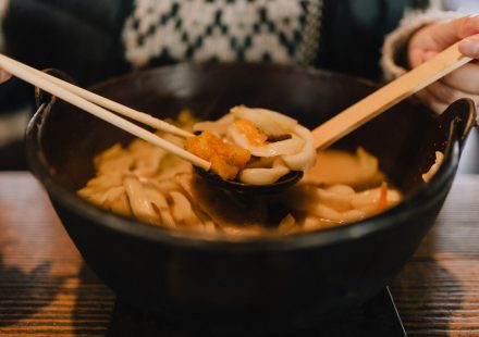 일식집 메뉴판 옆에 놓인 따뜻한 우동 한 그릇