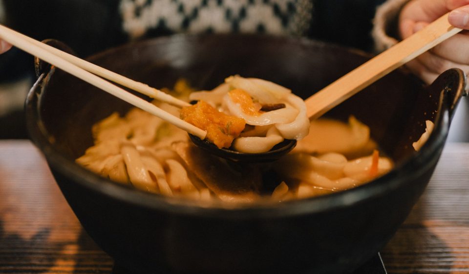 일식집 메뉴판 옆에 놓인 따뜻한 우동 한 그릇