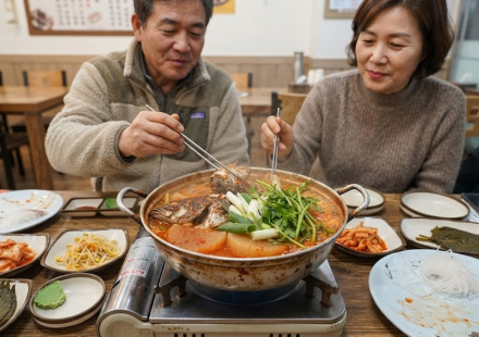 매운탕 이름 뜻 횟집 식탁에서 생선 머리와 무 대파가 끓고 있는 매운탕 냄비
